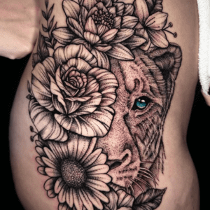 A black-and-grey upper arm tattoo of a tiger surrounded by detailed flowers.